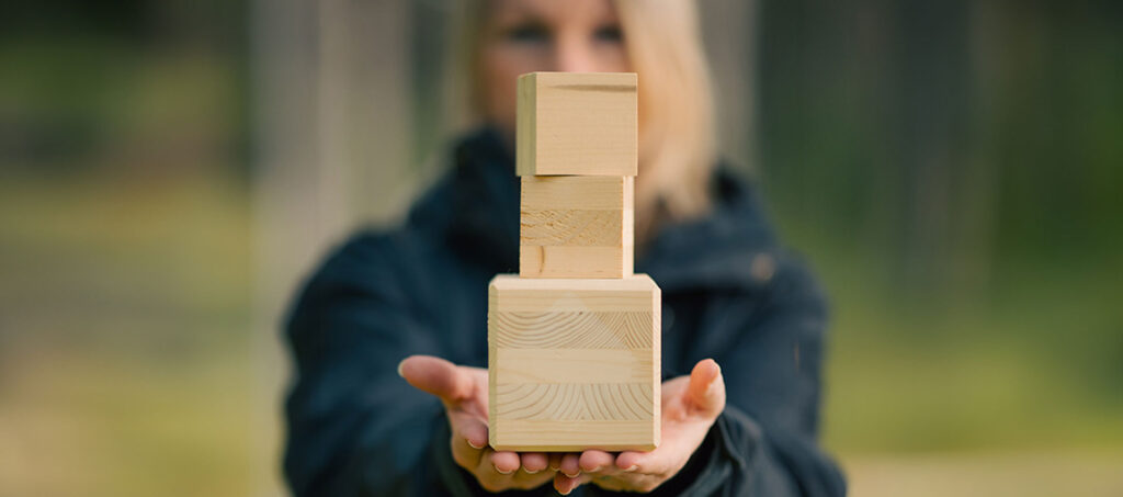 tjej håller fram tre träklossar staplade på varandra